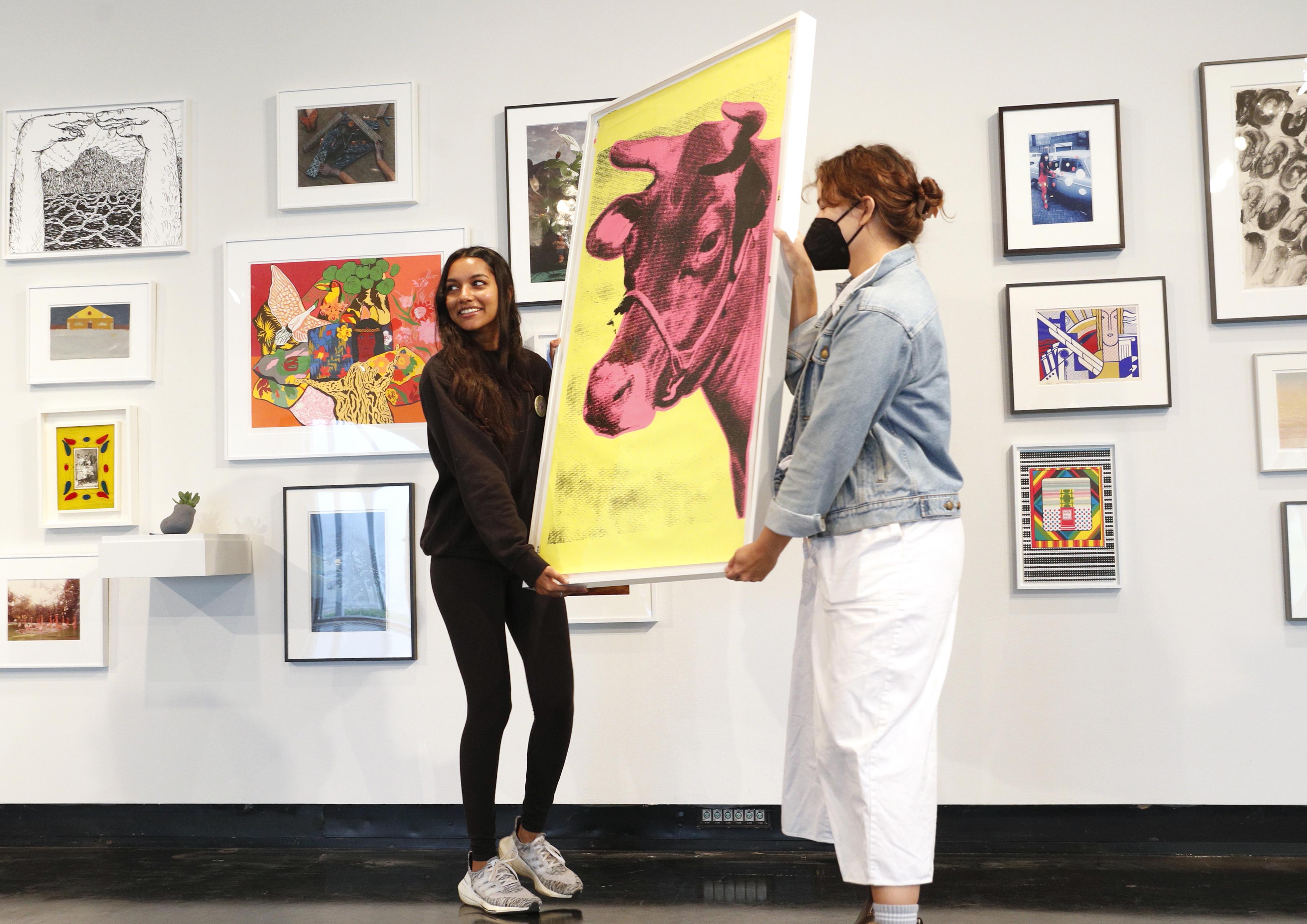 Qavalina Andrade ' 25, right, 与学生艺术贷款项目协调员凯尔西·伦科一起挑选安迪·沃霍尔的版画. 