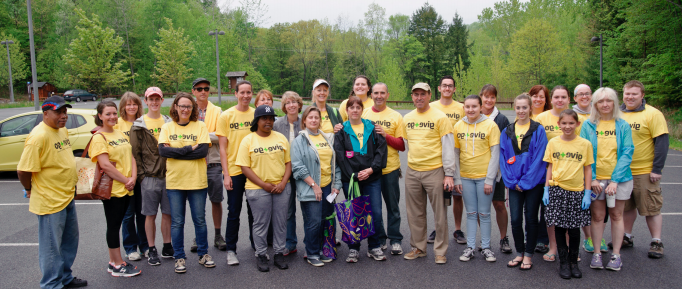 team of volunteers wearing bright yellow shirts line up in parking lot before the event